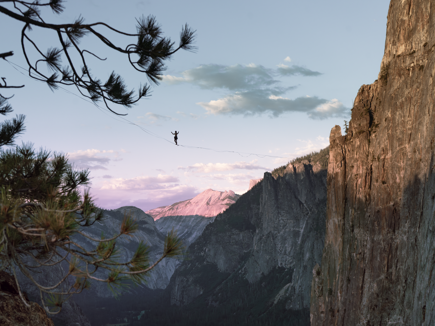 A photo print featuring a person highlining in Yosemite Valley during golden hour, with a mountain and pine trees in the background.