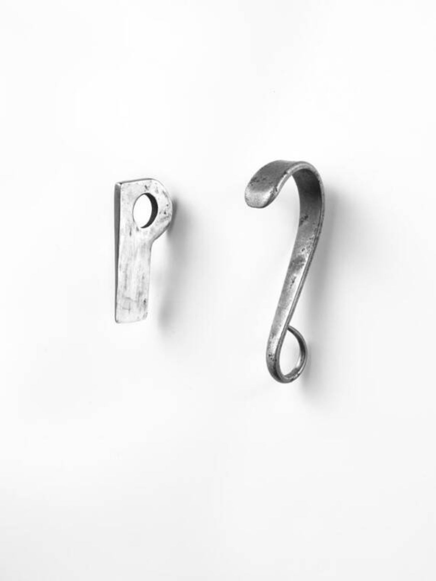 A photo print featuring two metal hooks, one shaped like a cobra's head and the other resembling a blade, against a white background.