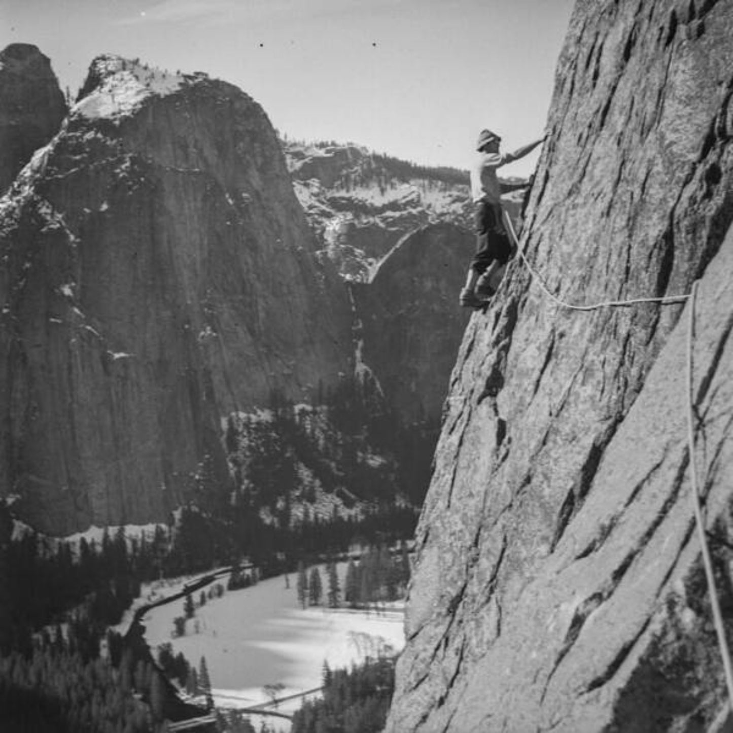 Black and white photo print of a person climbing on a mountain, with a scenic view of the valley in the background.