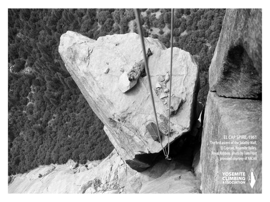 A black and white photograph of a climber resting on top of a rocky outcropping, with trees and a sky background.