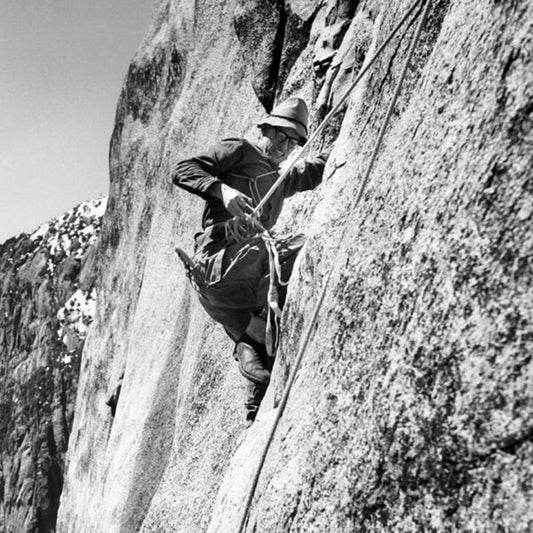 Black and white photo print featuring a person climbing a rock face, likely El Capitan, with a white border around the image.
